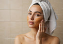 Young Woman Applying Gold Facial Mask in Spa Setting
