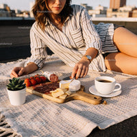 Woman enjoying outdoor charcuterie board with coffee