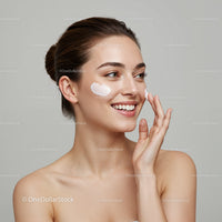 Beautiful Woman Applying Cream on Cheek with Skincare Products
