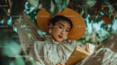 Stylish Woman Wearing Straw Hat Reading Book Outdoors in Garden