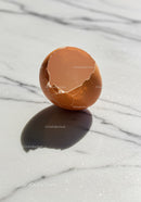 Cracked brown eggshell casting shadow on marble surface