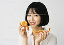 Smiling Woman Holding Fresh Orange Slice with Vibrant Citrus Colors