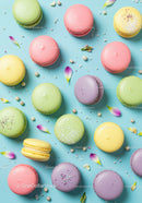 Colorful macarons scattered with flower petals on blue