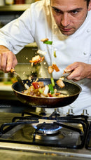 Chef Tossing Stir-Fry Vegetables Over Gas Stove