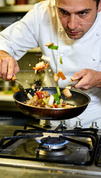Chef Tossing Stir-Fry Vegetables Over Gas Stove