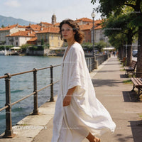 Woman in Flowing White Dress Walking by Lakeside Path