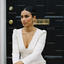 Elegant woman in white dress posing near black door