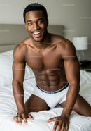 Smiling muscular man in white underwear on bed