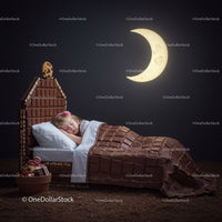 Little girl sleeping in chocolate themed cozy bed at night