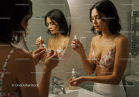 Young Woman Applying Skincare Routine in Bathroom Mirror
