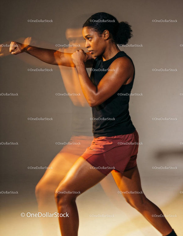 Focused woman practicing boxing punches in motion