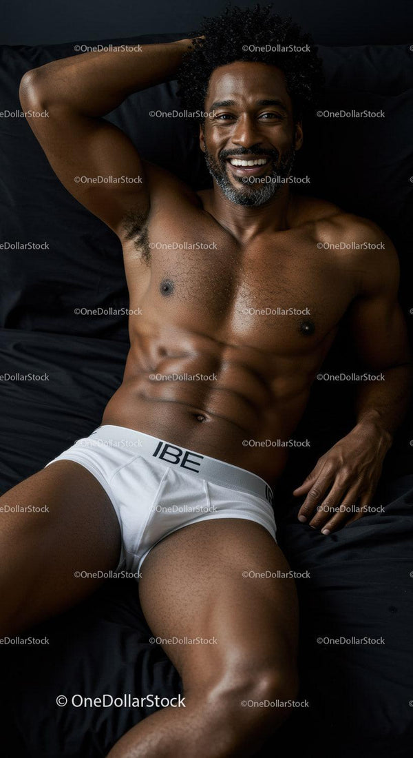 Smiling muscular man relaxing on dark bed in white briefs