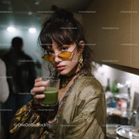 Stylish Young Woman in Gold Blouse with Green Juice and Yellow Sunglasses