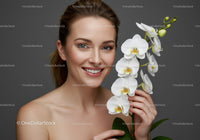 Smiling Woman Holding White Orchid Flower in Front of Gray Background