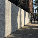 City Sidewalk with Brick Wall and Pedestrians in Urban Environment