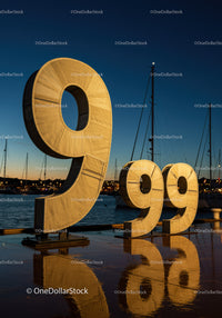 Large illuminated 999 sculpture at harbor dusk