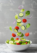 Fresh vegetable salad ingredients falling into bowl