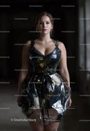 Elegant Woman in Glossy Black Floral Dress Standing against Dark Background