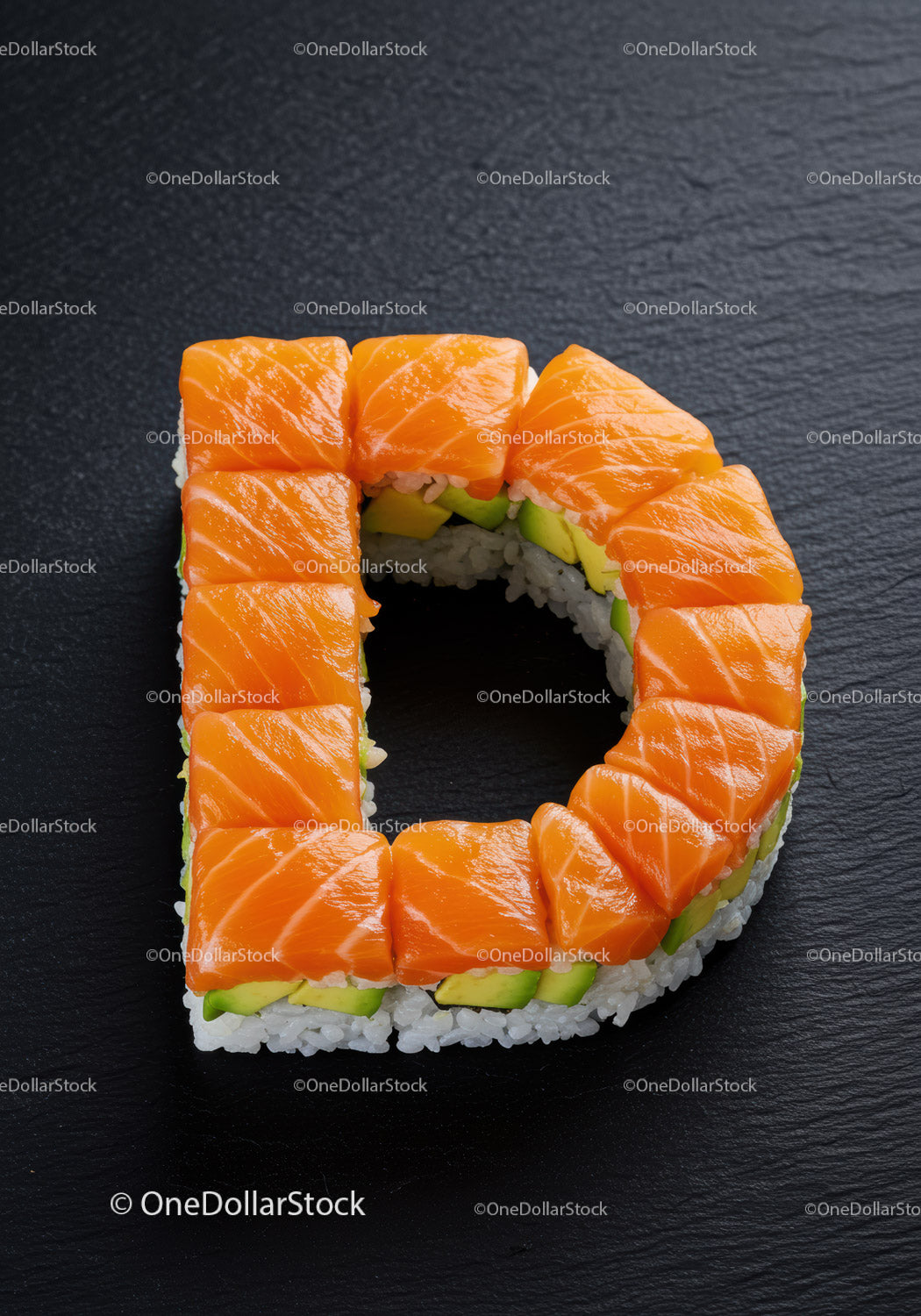 Salmon Sushi Roll Shaped as Letter D on Black Slate