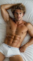 Relaxed muscular man lying on white bed linens