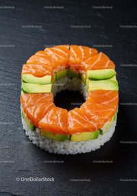 Ring-shaped salmon avocado sushi on dark slate surface