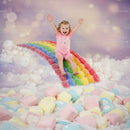 Joyful toddler sliding down rainbow candy hill