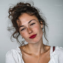 Young Woman with Curly Hair and Freckles Wearing White Blouse