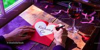 Writing a heartfelt love note beside wine glass