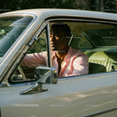 Young Man in Pink Shirt Driving Vintage Car in Green Scenery