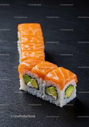 Fresh salmon avocado sushi roll on black slate