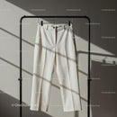 Minimalist white trousers hanging on black rack