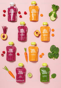 Colorful vegetable and fruit smoothie pouches on pink