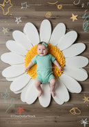 Cute baby lying on giant flower decoration indoors