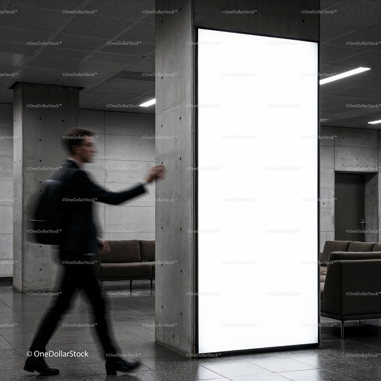 Businessman walking past illuminated blank billboard indoors