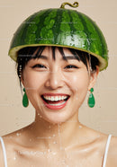 Smiling woman wearing watermelon hat with water splashes