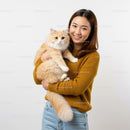Smiling woman holding fluffy cream cat indoors