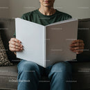 Person Holding Blank Open Book While Sitting on Sofa