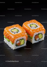 Fresh salmon avocado sushi rolls on black slate
