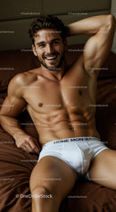 Smiling man relaxing on bed in white underwear