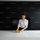 Young woman arranging lemons on sleek white kitchen counter