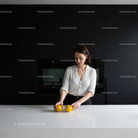 Young woman arranging lemons on sleek white kitchen counter