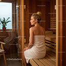 Relaxing Woman Sitting in Sauna with Wooden Interior and Towels
