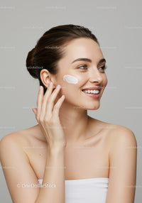 Young Woman Applying Skincare Cream with a Bright Smile