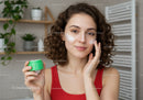 Young Woman Applying Face Cream for Skincare Routine with Natural Lighting