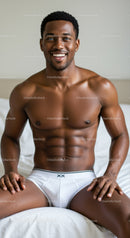 Smiling muscular man sitting on bed in white underwear