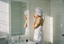 Woman Applying Skincare in Bright Minimalist Bathroom