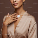 Elegant Woman Applying Moisturizer on Her Neck Against Brown Background