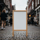 Blank wooden A-frame sidewalk sign on urban cobblestone street