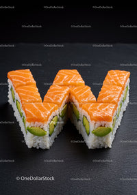 Salmon and avocado sushi shaped as letter W on dark slate