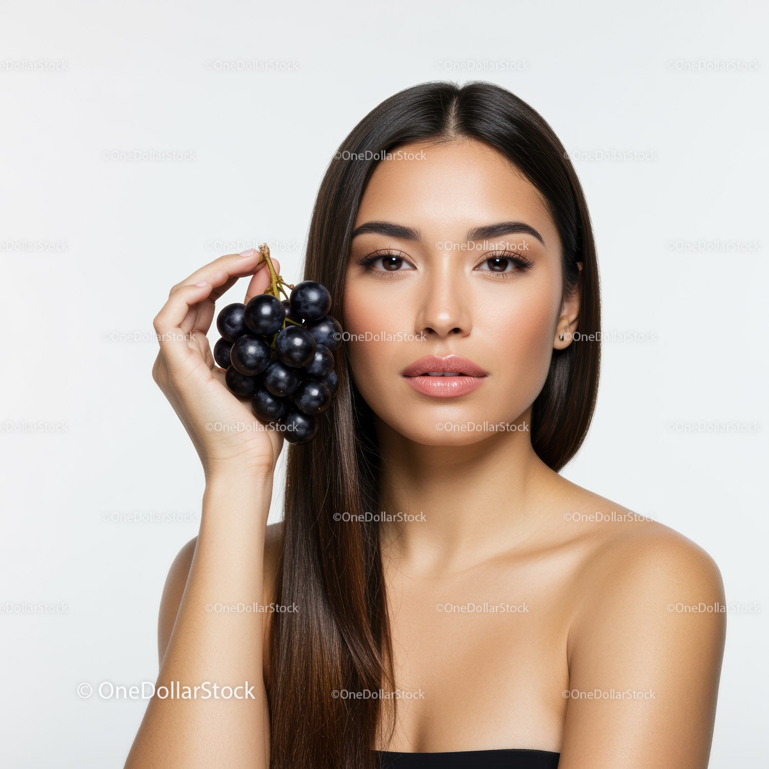 Young Woman with Long Brown Hair Holding Black Grapes in Studio